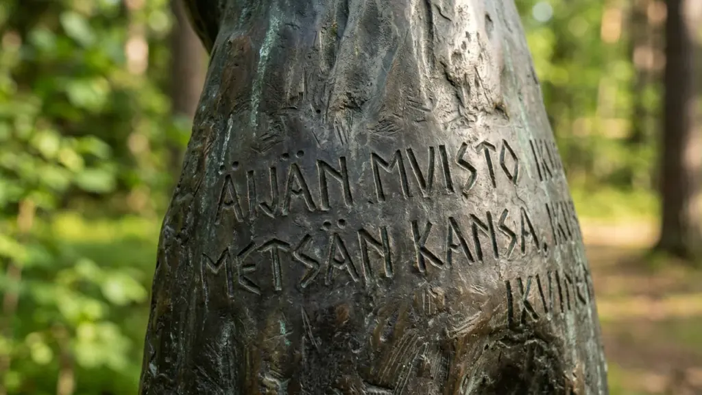 Lähivõte pronksist skulptuurist, millele on graveeritud soomekeelne tekst metsa ja rahva kohta.