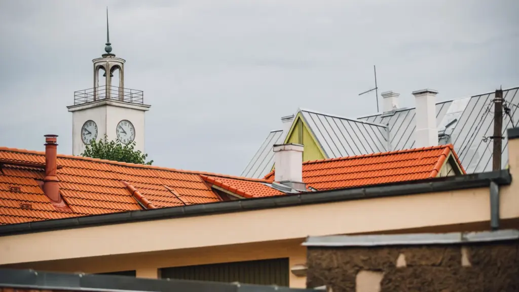 Vaade vanalinna punastele katustele ja taustal kõrgub valge kellatorn pilvise taeva all.