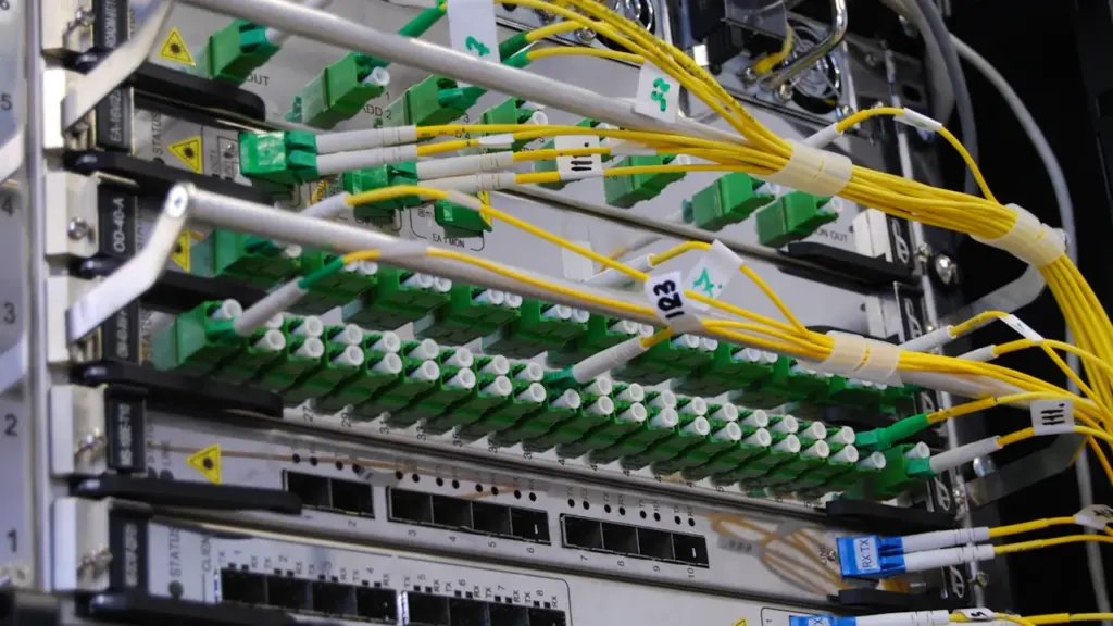 Fiiberoptilised kaablid ühendatud võrguseadmetega serveriruumis, näidates kaasaegset sidevõrgu tehnoloogiat ja infrastruktuuri.